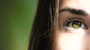 A detailed close-up of a woman's eye with green iris, capturing beauty detail.